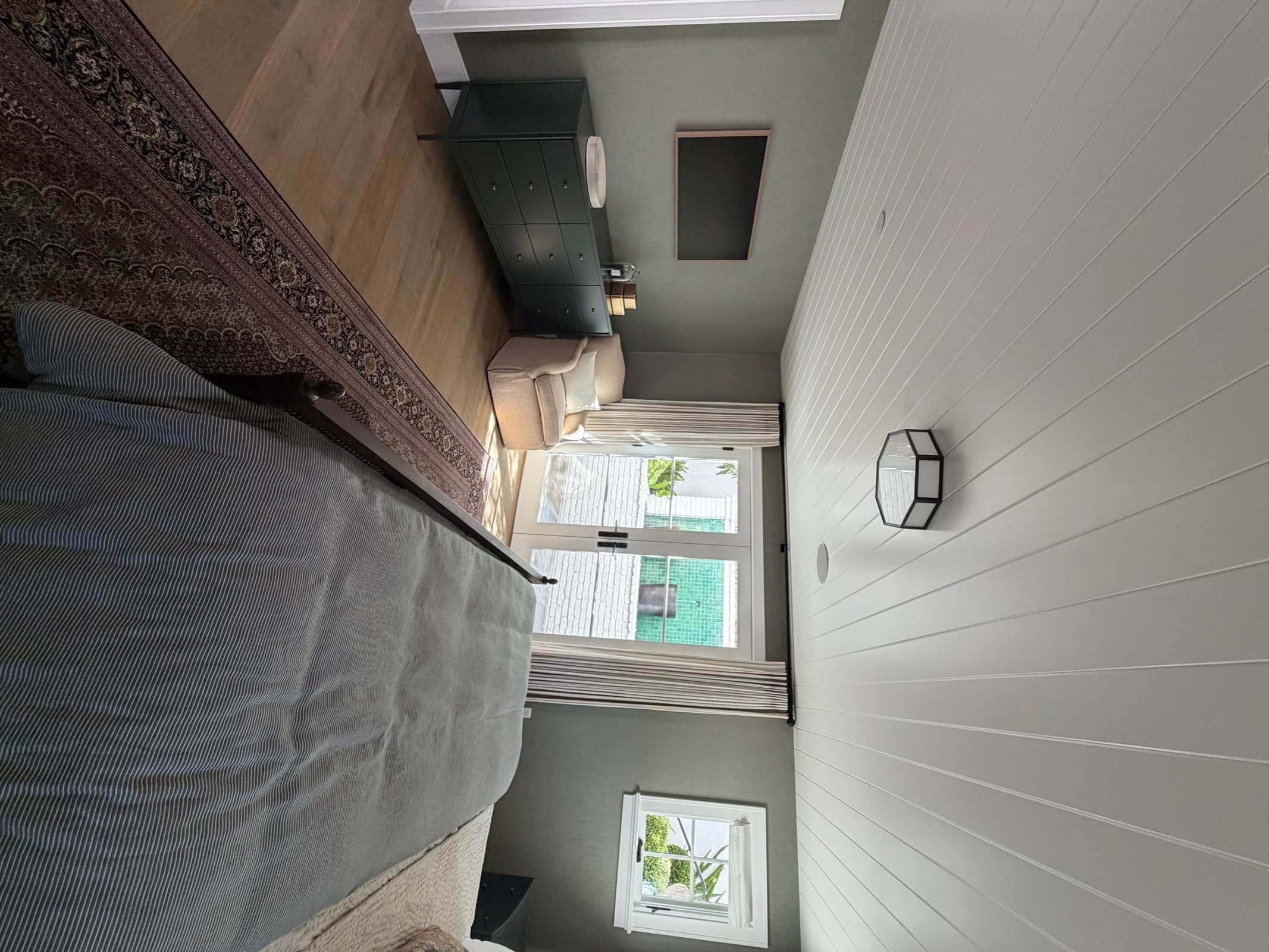 Finished bedroom with oak flooring, green walls, and French doors to the patio