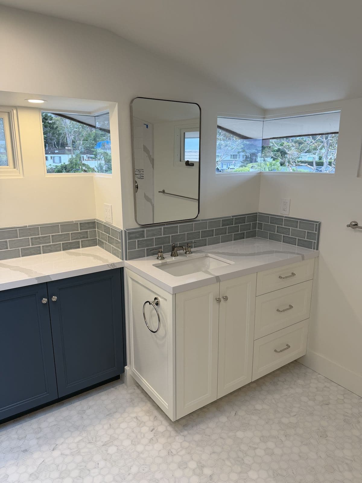 White vanity with gray subway backsplash and black-framed mirror