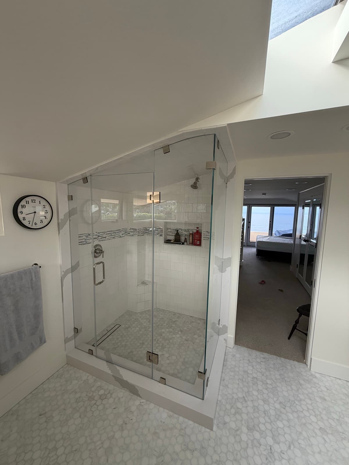 Corner shower with built-in bench and niche, opening to the bedroom beyond