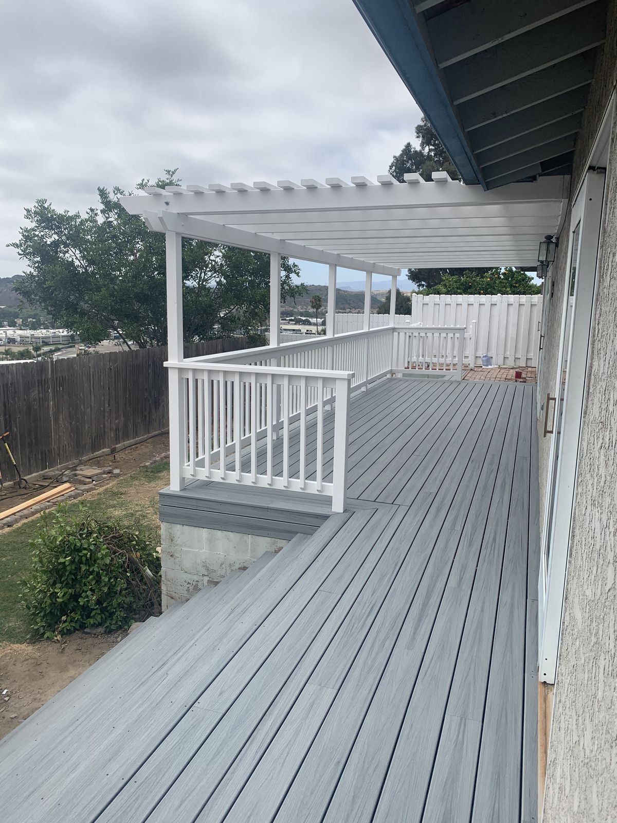 Deck under the white pergola looking out over the fence line