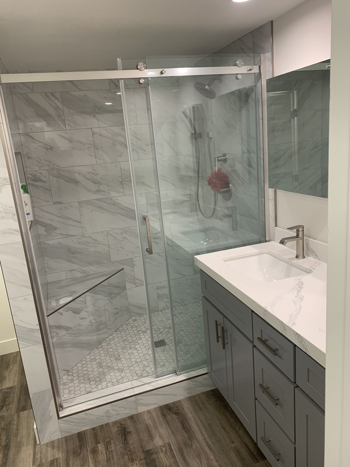 Walk-in shower with sliding glass door, rain head, and hex-tile pan